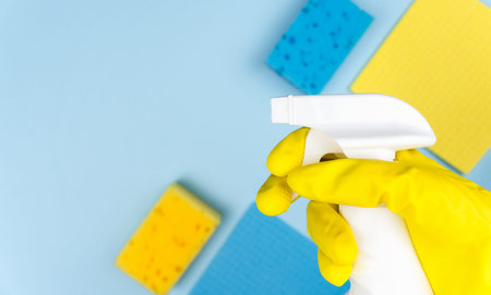 A woman's hand in a rubber glove holding a spray cleaner. Spring cleaning concept. Top view. Copy...