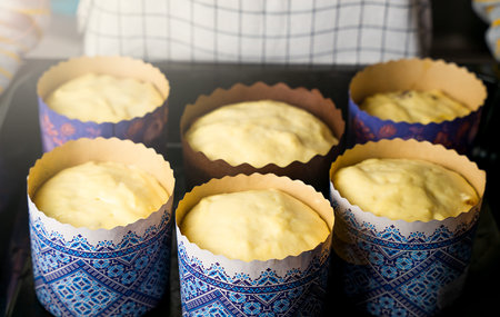 Woman holding baking tray with Easter cakes in the paper form. Close-up. Selective focus.
