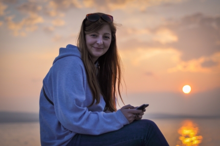 Pretty girl smiling at seaside in sunsetの写真素材