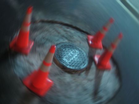 Construction Cones with Drain Blur created from a picture of a manhole cover and 4 orange cones.の写真素材