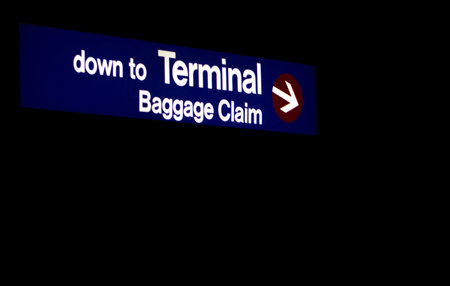 Down to Terminal Baggage Claim is a sign giving directions as to where people can pick up their luggage at an airport terminal.の写真素材