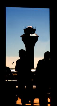 Silhouette of Airport Tower and Passengers Waiting captured in this uniquely framed picturesque of the aviation transportation industry.の写真素材