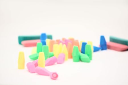 Pile of erasers for school supplies on a white background. Focus is on the yellow eraser standing next to the pink erasers lying down. の写真素材