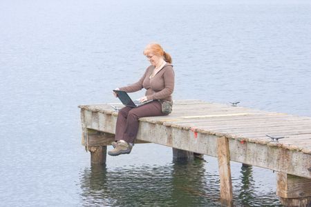 Attractive Redhead Woman uses Laptop on the Pier at Lake Washington.の写真素材