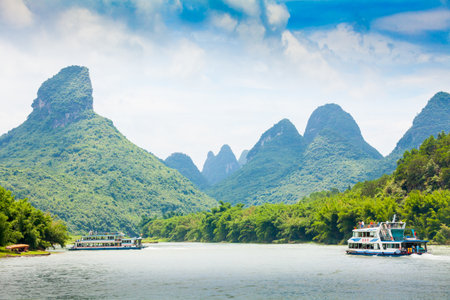 Guilin China July 2011: In July tourists get on these motor boats to go some miles down the river Li offering gorgeous views with views of the tall karst peaks covered with dense vegetationのeditorial素材