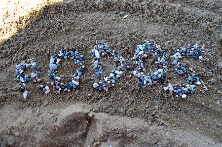 Inscription of Rhodes with colorful stones on the beach. Against the background of sand.の写真素材