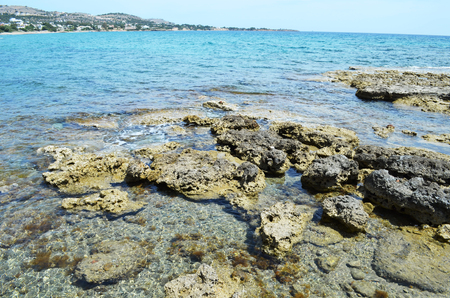 The shore of the Mediterranean Sea at the head of Rhodes. Filled with volcano stones, overlooking the small town.の写真素材