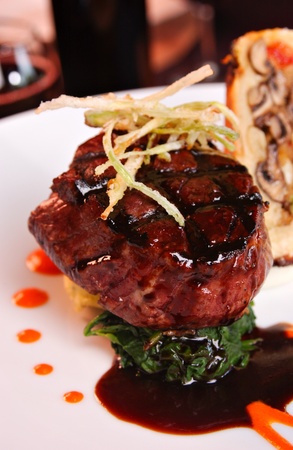 Grilled filet Mignon over mashed potatoes & spinach, topped with .  Roasted garlic cloves are also displayed.の写真素材