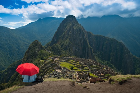 A tourist under the shade of a red umbrella looking at Machu Picchu. のeditorial素材