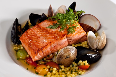 Beautifully plated salmon fillet garnished with colorful green parsley.  Served over a couscous and seafood salad featuring mussels, clams, tomatoes and brussels sprouts.
の写真素材