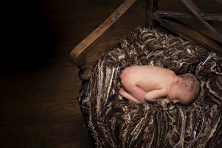 Newborn boy asleep on blankets on wooden bench. の写真素材