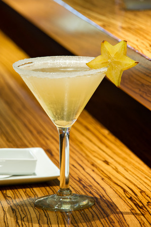 Tropical Martini cocktail with a star fruit garnish.  Shot on a wood grain surface.の写真素材