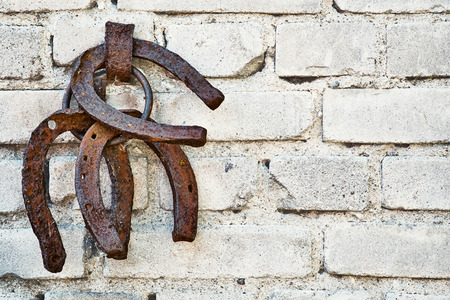 Three old rusty horsheshoe on white brick wall - sign of happinessの写真素材