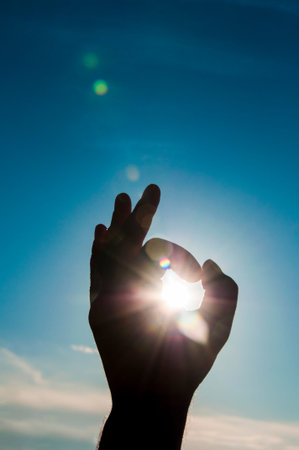 Sun in the hand on blue sky. Freedom, harmony, spirituality concept.の写真素材