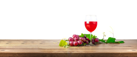 Red wine glass and bunch of grapes on wooden table. Selective Focus, Focus on the front part of bunch grapesの写真素材