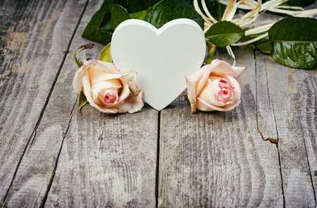 White Wooden Heart And Beautiful Roses On Old Wooden Table. Love Concept.の写真素材