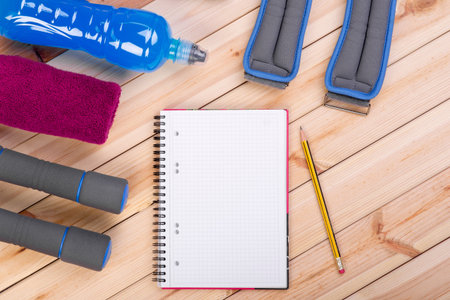 Sport Equipment. Dumbbells,  Ankle Weights, Towel, Isotonic Drink And Notebook To Workout Plan On Boards. Sport Fitness Backgroundの写真素材