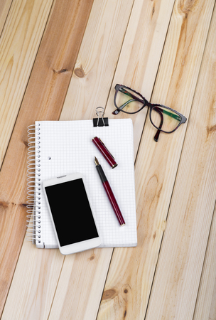 Office Desk With Notepad, Smart Phone, Glasses And Fountain Pen On Wooden Desk.の写真素材