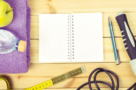 Jump Rope, Towel, Tape Measure, Apple, Bottle Of Water, Notepad To Workout Plan On Wooden Floor. Sport Fitness Background In Retro Styleの写真素材