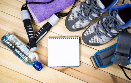 Jump Rope, Ankle Weights, Sport Shoes, Towel, Bottle Of Water And Notepad To Workout Plan On Wooden Floor. Sport Fitness Backgroundの写真素材