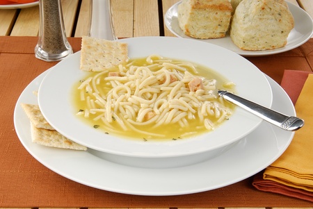 A bowl of chicken noodle soup and soda crackersの写真素材