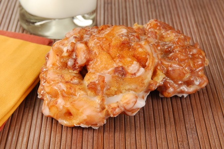 Two apple fritters on a placemat with milkの写真素材
