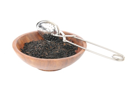 Organic whole leaf black poemgranate tea with an infuser in a wooded bowlの写真素材