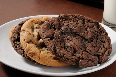 A plate of chocolate chip cookies with a glass of milk