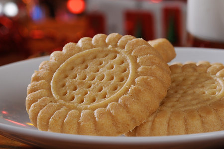 Closeup photo of a gourmet shortbread or butter cookie with Christmas decorations in the background