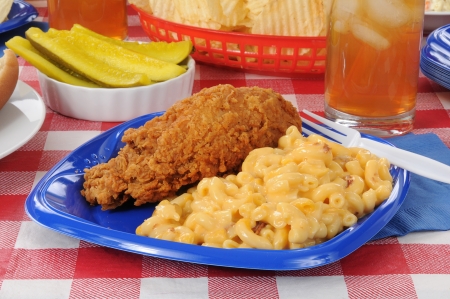 A plate of fried chicken and macaroni on a picnic tableの写真素材