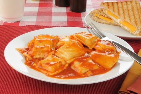 A large bowl of beef and cheese ravioli with a sandwichの写真素材