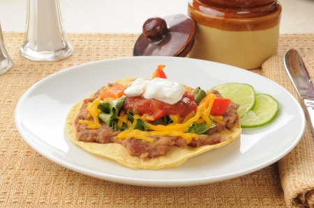 A tostada with refried beans, cheddar cheese and lettuceの写真素材