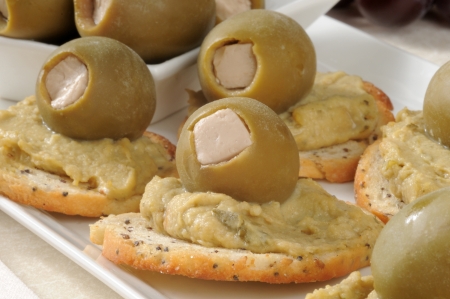 Closeup of hummus on sliced bagel toasts with green olives and geta cheeseの写真素材