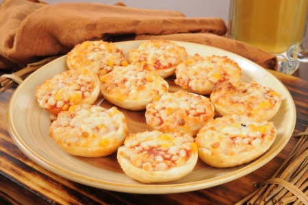 A snack plate of pizza bagels with a mug of beer in the backgroundの写真素材