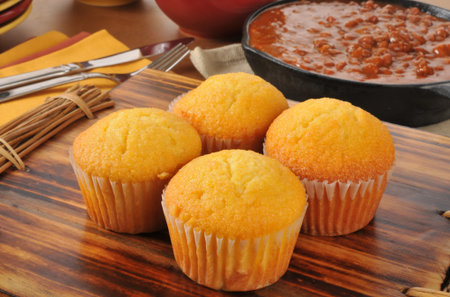 Corn bread muffins with a cast iron skillet of chili con carne in the background