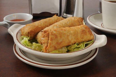 A plate of chicken egg rolls with sweet and sour sauce
