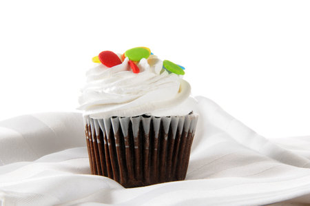 A gourmet cupcake with candy sprinkles on a high-key set
