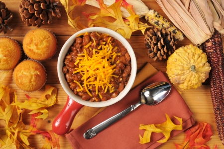 A stoneware crock of chili con carne with cornbread muffins and cheddar cheeseの写真素材