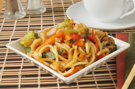 a bowl of chicken chow mein with a cup of teaの写真素材