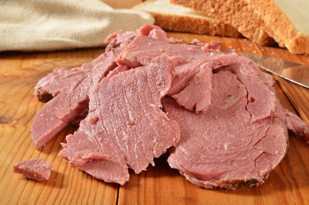 A mound of home cooked sliced roast beef on a rustic wooden cutting boardの写真素材