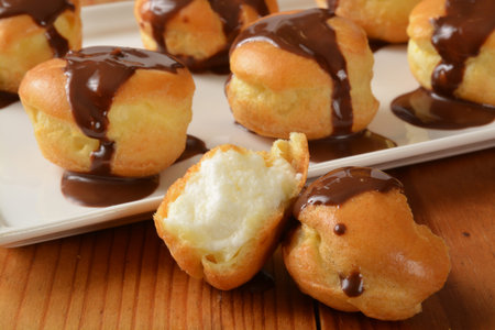 Closeup of vanilla cream puffs with chocolate sauce, shallow depth of field