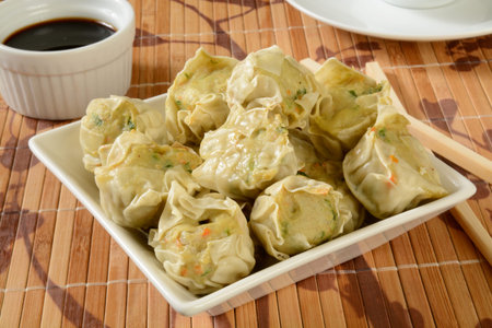 A bowl of chicken and vegetable dumplings with soy sauceの写真素材