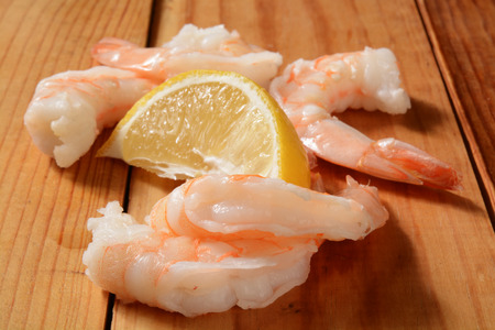 Large shrimp prawns on a rustic wooden table with a wedge of lemonの写真素材