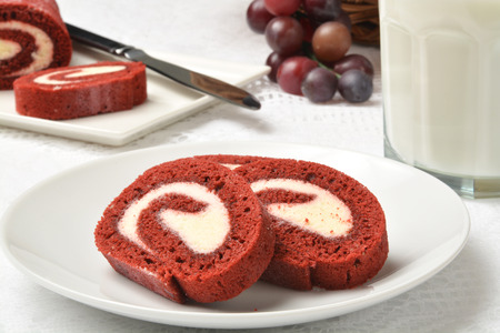 Sliced red velvet cake roll with a glass of milkの写真素材