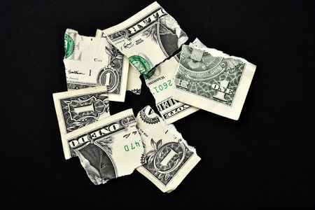 A shredded dollar bill on a black backgroundの写真素材