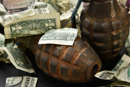 torn and crumpled money and hand grenades indicating an explosive economy and economic destructionの写真素材