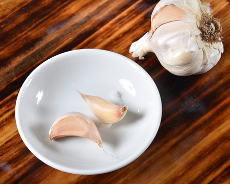 Fresh garlic bulb and cloves in a spice bowlの写真素材