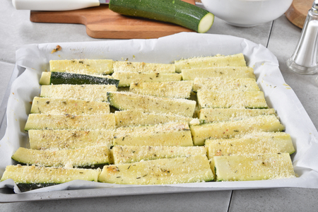 Zucchini wedges seasoned with olive oil, garlick and parmesan cheese in a baking pan ready for the ovenの写真素材