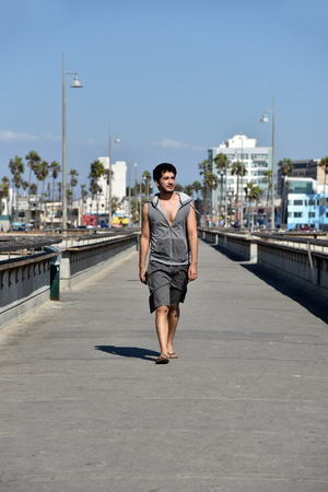 Handsome young male tourist walking on the fishing pier at Venice Beach in Southern California.の写真素材