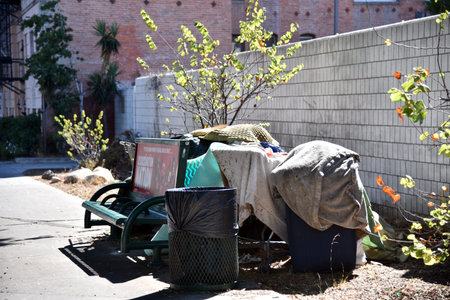 LOS ANGELES, CA/USA - APRIL 18, 2019: Homeless people build shelters behind bus stop benches on Vermont street across from trendy restaurantsのeditorial素材